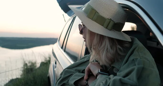Beautiful Traveler Girl in Hat and Sunglasses Sitting in Car Enjoying Road Trip Near Canyon River