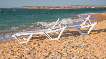Fototapeta na wymiar Sun loungers stand on a sandy beach by the sea