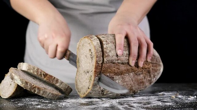 Hand Cutting Fresh Whole Grain Bread On The Table.