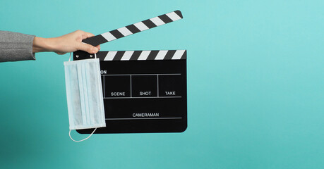 Hands with grey suit and hold black Clapper board or movie slate with face mask. it use in video...