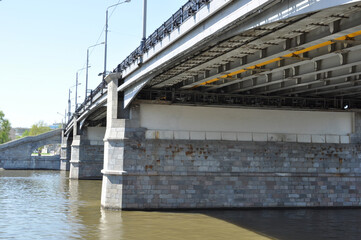 Panoramic view of the river and the stone pillars of the bridge. Sunny day, blue sky.