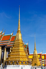Fototapeta premium Golden pagoda with demon guardian at The Wat Phra Kaew or the temple of the Emerald Buddha within the grounds of the Grand Palace in Bangkok, Thailand