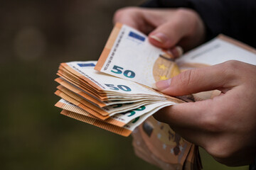 Selective focus shot of a female hand counting euro banknotes - obrazy, fototapety, plakaty