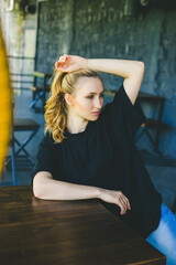 Naklejka premium young woman is sitting at a table in a cafe. The girl looks away.