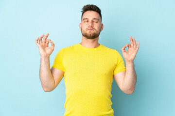 Fototapeta premium Russian handsome man isolated on blue background in zen pose