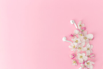 Flat lay on pink background with apple blossom ornament and earphones
