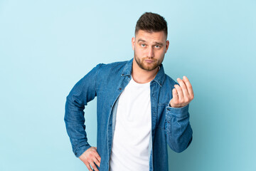 Russian handsome man isolated on blue background making Italian gesture