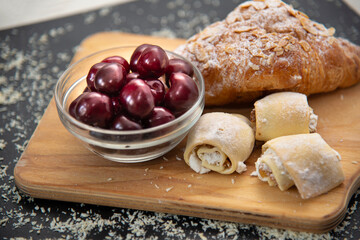 Dark red cherry berries and homemade cookies and croissant. Dessert concept