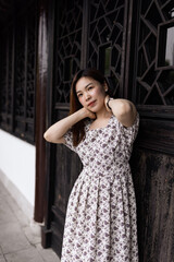 Fototapeta premium Portrait of young asian woman wearing stylish summer dress and walking outdoor in old city. Happy stylish woman with smiley face enjoys life