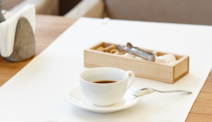 Hot coffee in a cup on wooden table. Modern design interior, restaurant blur background with bokeh image