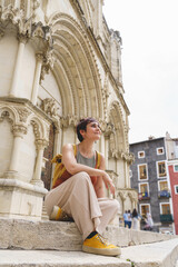 Vertical view of tourist woman sit on an urban square with a gothic cathedral in the background sightseeing in an european city. Travel and holidays concept in Spain.
