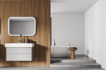 White and wooden bathroom interior with sink and mirror, bathtub with towels