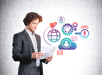 Handsome businessman in suit checking documents, digital icons on concrete wall. Office network communication icons, technology, data security and personal information