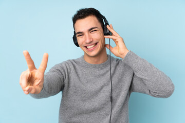 Fototapeta premium Young caucasian handsome man isolated on blue background listening music and singing