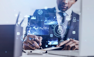 Black businessman writing a note, glowing hologram with lock and icons