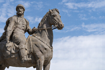 Obraz premium Medieval Russian prince on horseback. Close-up stone sculpture against the backdrop of a beautiful blue sky with clouds.