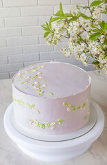 Wedding pink cake cake on a stand among branches of cherry blossoms. delicate decor on cake