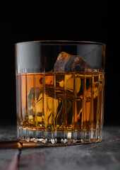 Single malt scotch whiskey in crystal glass with ice cubes on wooden background