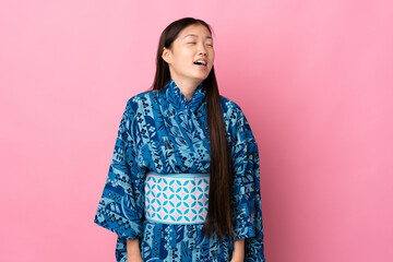 Young Chinese girl wearing kimono over isolated background laughing