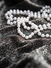 A string of pearls on a shiny black fabric