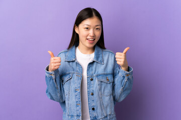 Young Chinese girl over isolated purple background giving a thumbs up gesture