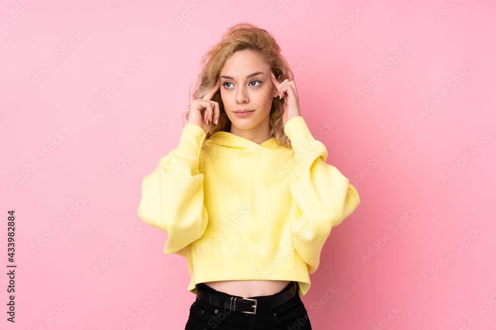 Poster Young blonde woman wearing a sweatshirt isolated on pink background having doubts and thinking