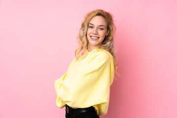Young blonde woman wearing a sweatshirt isolated on pink background with arms crossed and looking forward