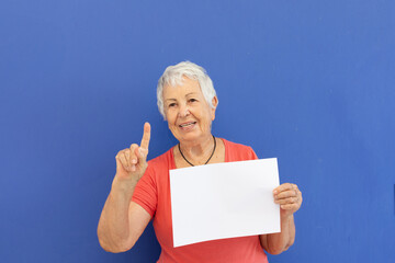 Mulher idosa gesticula com cartaz em branco para anuncio