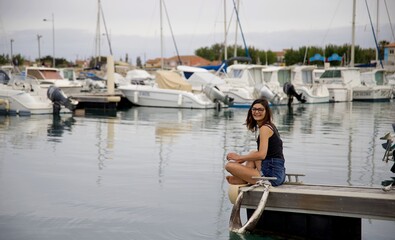 Jeune femme brune souriante en vacances au bord de mer - bateau voilier port darse dock - tourisme...