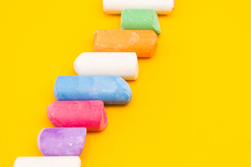 Children's drawing crayons lie in a row on a yellow background.