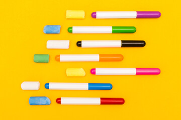 Multi-colored markers and crayons on a yellow background. Photo for drawing.