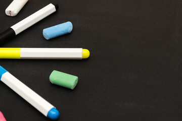 Multicolored markers in the shape of a star on a black background.