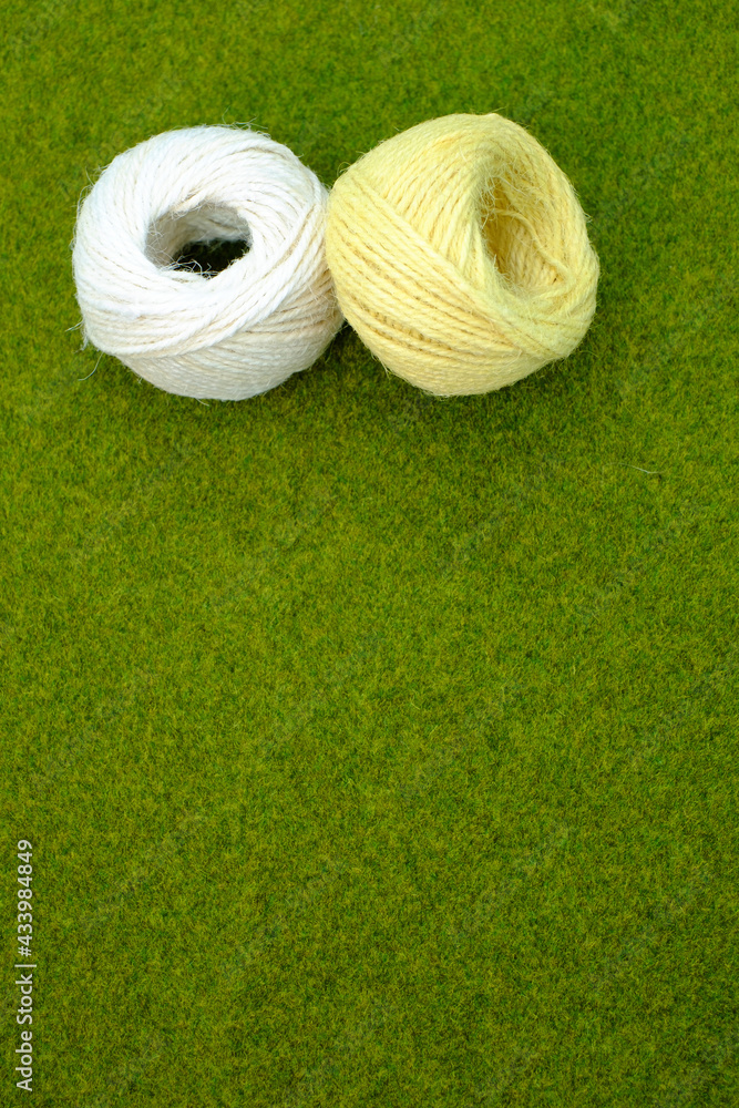 Wall mural Vertical shot of yellow and white thread yarns on the grass with a copy space