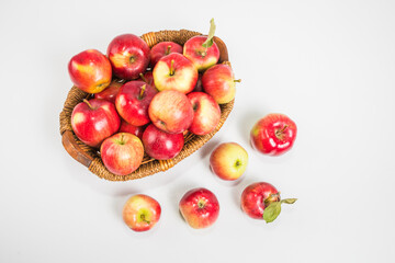 Bright multi-colored fresh apples in a wicker basket on a white background. Selective focus.