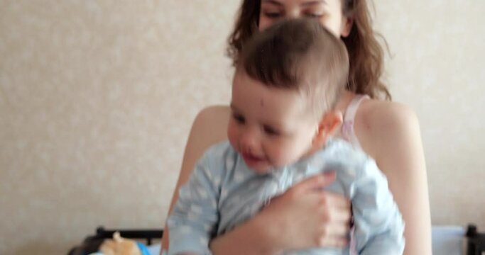 mom holds the baby in her arms and plays with him. Little cute Son plays with mom at home