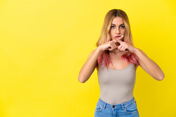 Young woman over isolated yellow background showing a sign of silence gesture