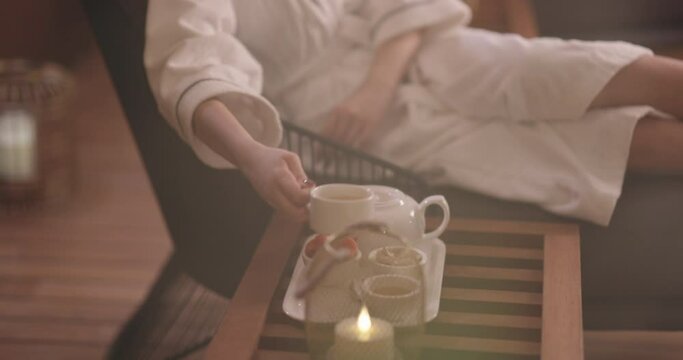 Mindful asian girl in white robe relaxing in oriental spa resort, drinking tea. Elegant woman relaxing, finding inner peace and balance - wellbeing portrait 4k footage