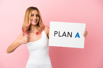 Young woman over isolated pink background holding a placard with the message PLAN A with thumb up