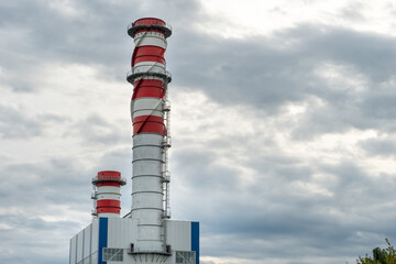 A large industrial smokestack against a blue sky. Red and white pipe in commercial enterprises or power plants.