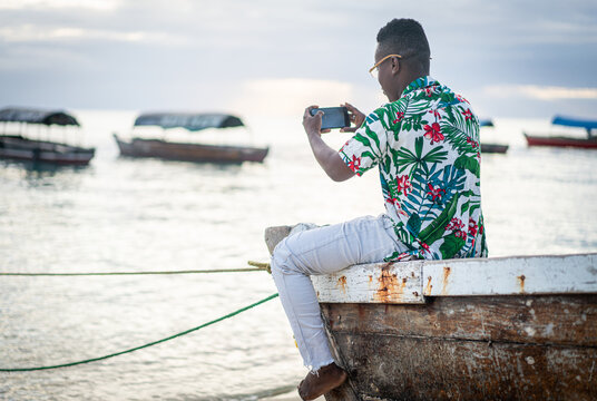 Young black man sitting on boat taking selfie alone