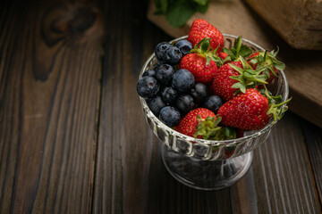 Berries in a bowl on a wooden table. Strawberries and blueberries
