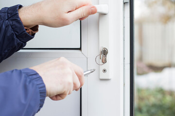 Handyman installing door lock in front plastic door with screwdriver. Checking lock for operability in door.