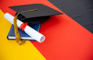 Graduation diploma and academic hat on the background of the flag of Germany. Concept - Graduation Day. German education.
