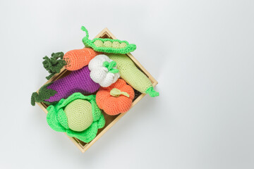 Children's food, toy knitted vegetables in a wooden box. Set for games in the kitchen, farm, vegetable garden, harvest