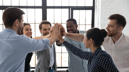 Business team of happy motivated staff employees giving joined hands high fives. Excited work group...