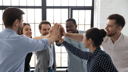 Business team of happy motivated staff employees giving joined hands high fives. Excited work group...