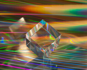 Glass cube on abstract holographic background close up.