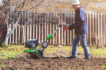 Farmer man plows the land with a cultivator preparing the soil for sowing