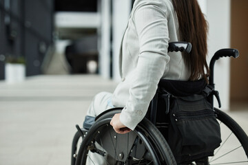Obraz premium Cropped portrait of young businesswoman in wheelchair entering office building, copy space