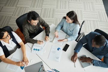 Top view at diverse business team discussing project at meeting table in office with focus on young...